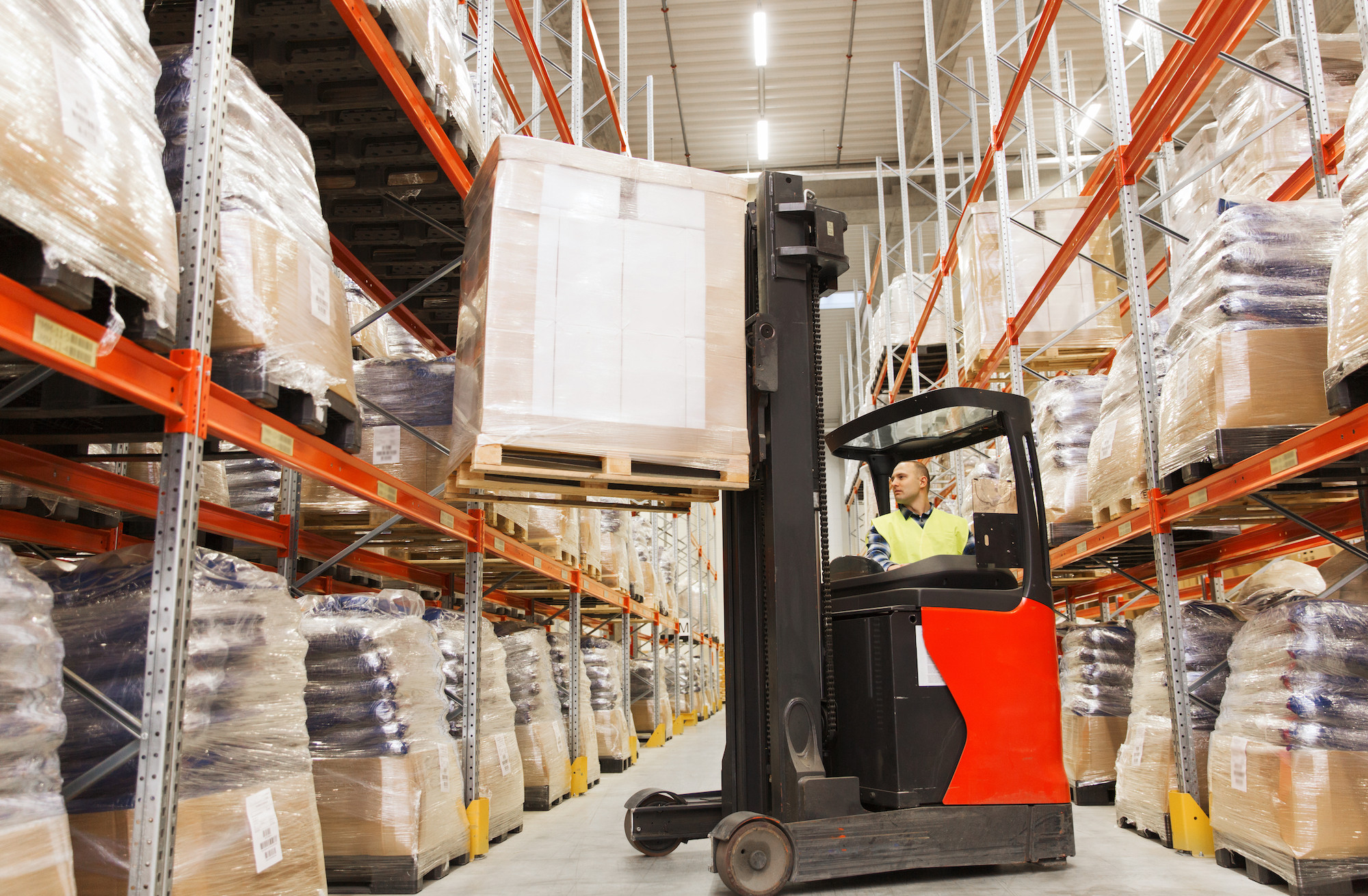Forklift driver placing a pallet in a warehouse